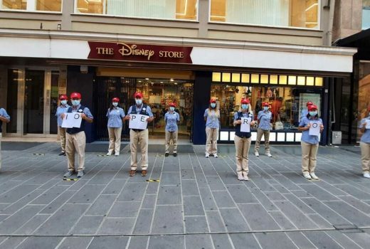 People stand in a row outside a Disney Store.