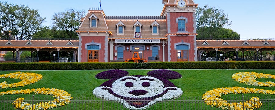 A train station on a hill, behind a garden made to look like Mickey Mouse.