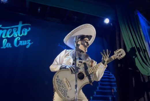 A skeleton man with sombrero and guitar leans forward.