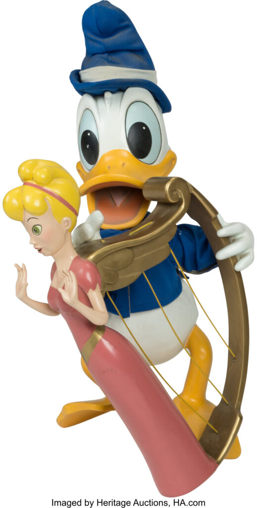A human-like duck holds a harp, which has an enchanted, living woman statue on its edge.