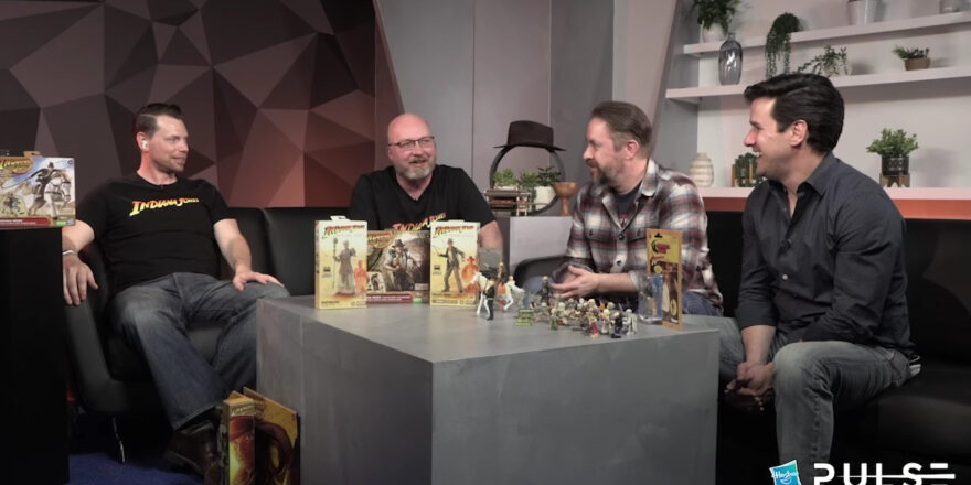 Four men sit at a table, with toys on it.