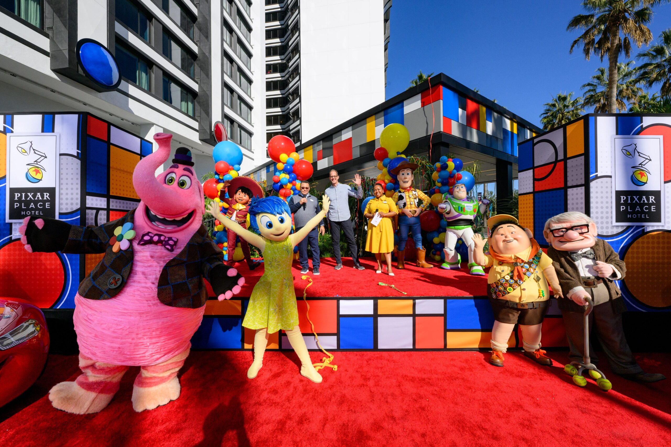 Various characters in front of a stage, in front of a hotel.