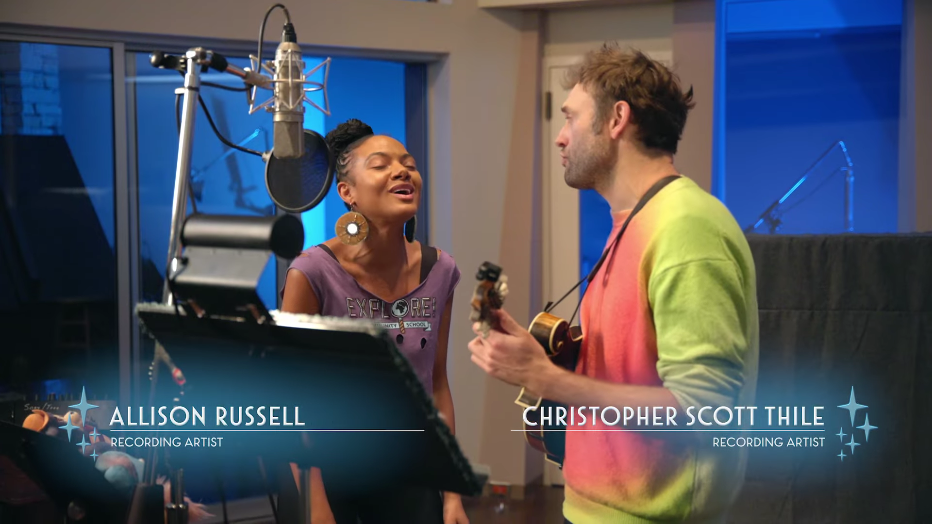 A woman and man sing in a recording studio.