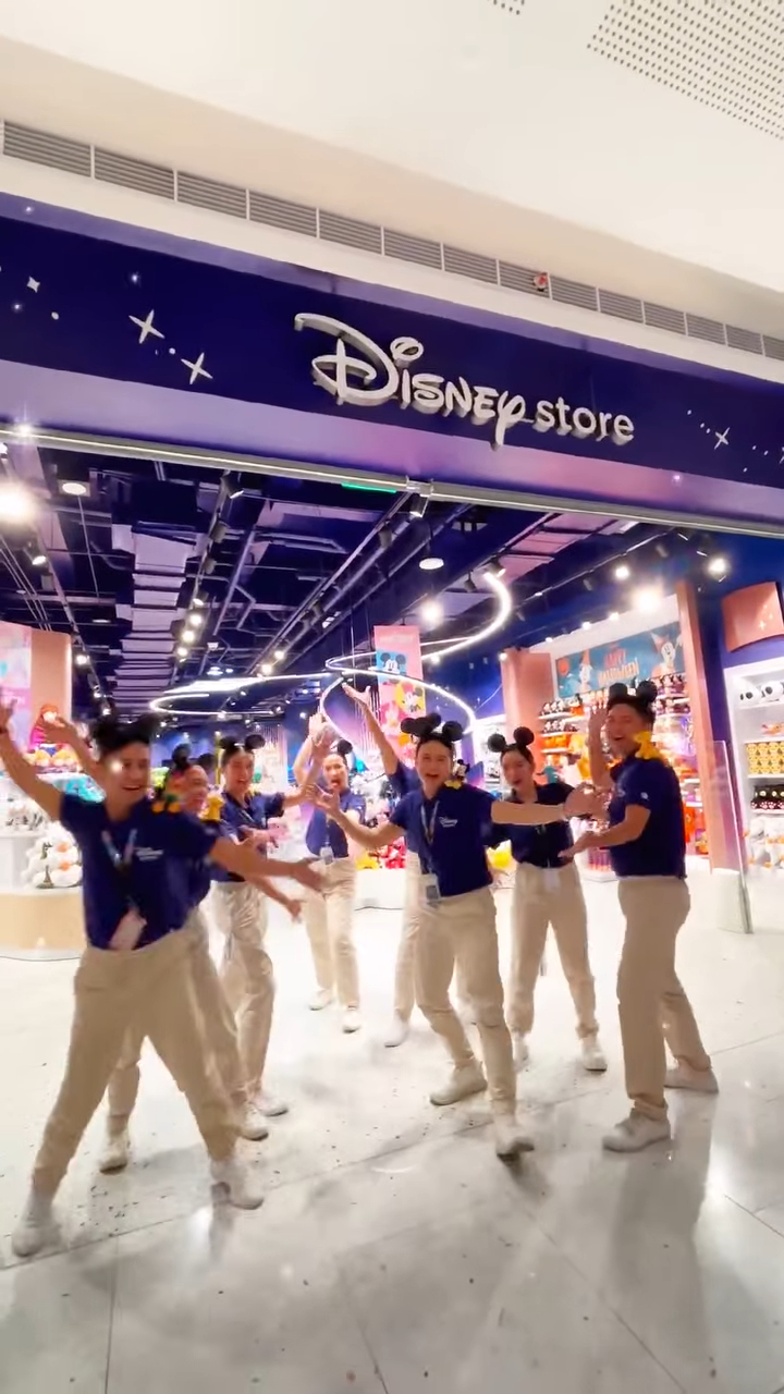 Disney Store employees pose in a dancing position.