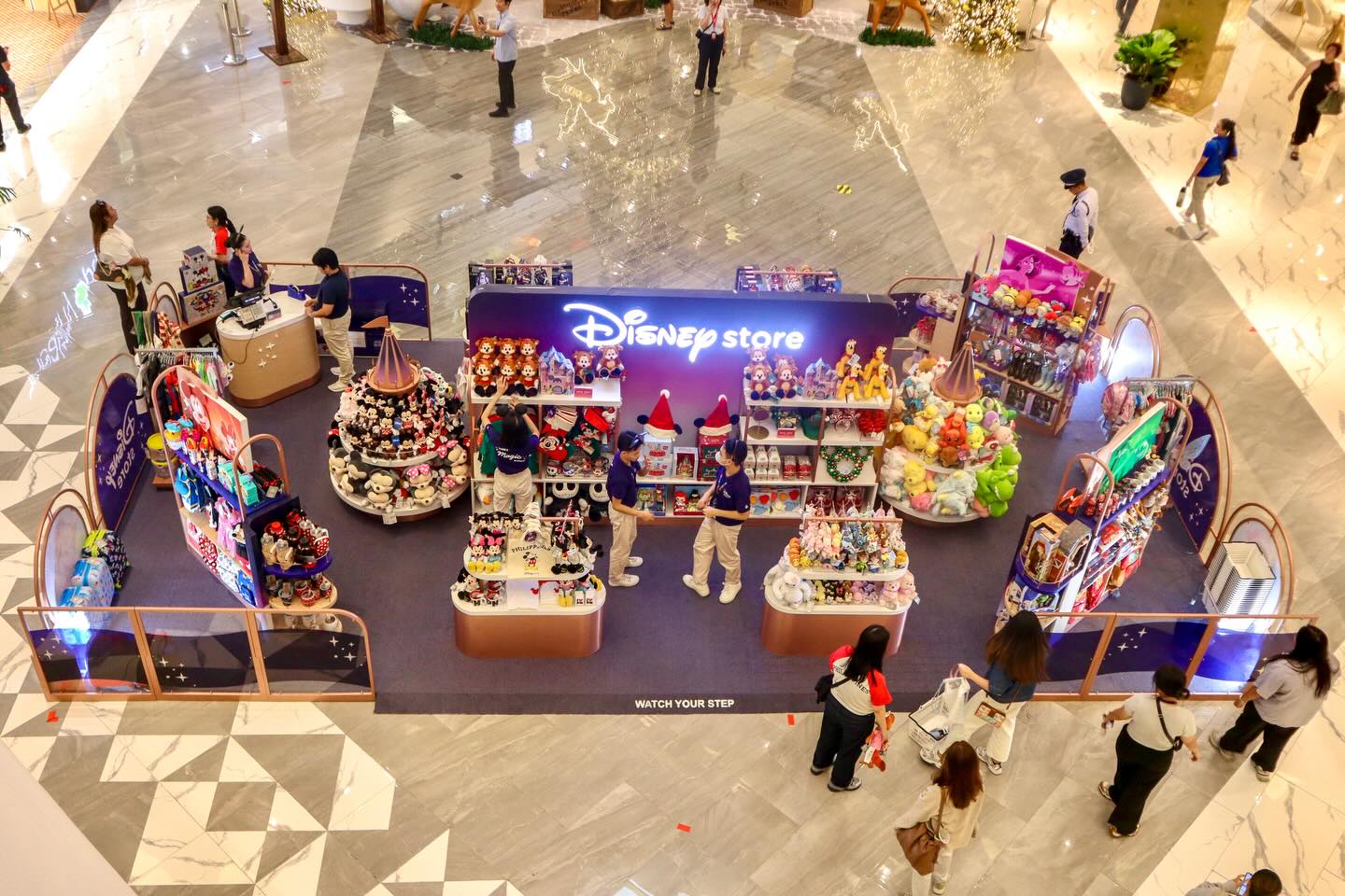 Overhead view, looking down at a series of Disney displays in the concourse of a mall.