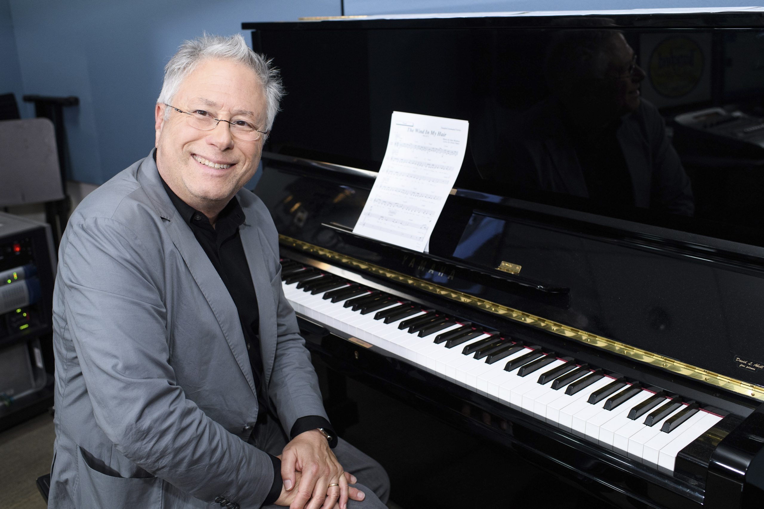 A man smiles at his piano.