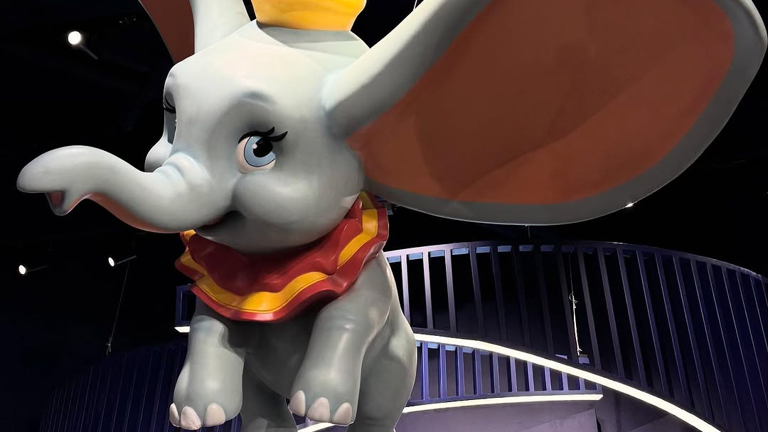 A statue of an elephant child with big ears, flying overhead of guests.