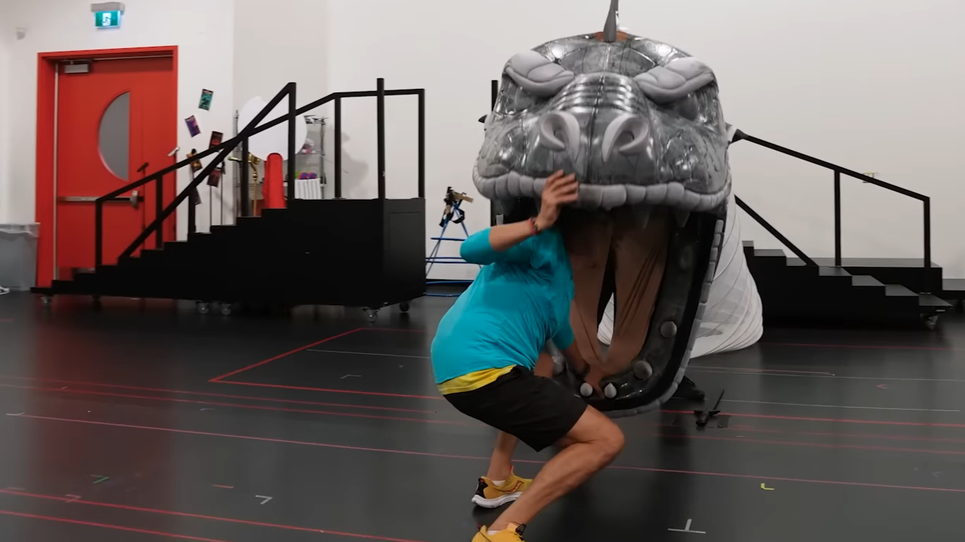 A puppet head of a hydra looks to eat a man.