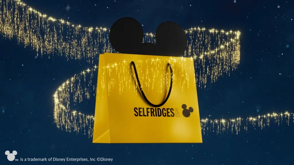 A yellow bag with the text Selfridges, an ampersand, and the silhouette of Mickey Mouse's head.