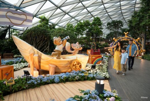 A garden with a boat statue, with a teddy bear statue and a cat stuffed toy statue.