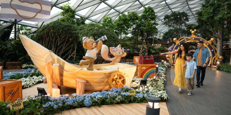 A garden with a boat statue, with a teddy bear statue and a cat stuffed toy statue.