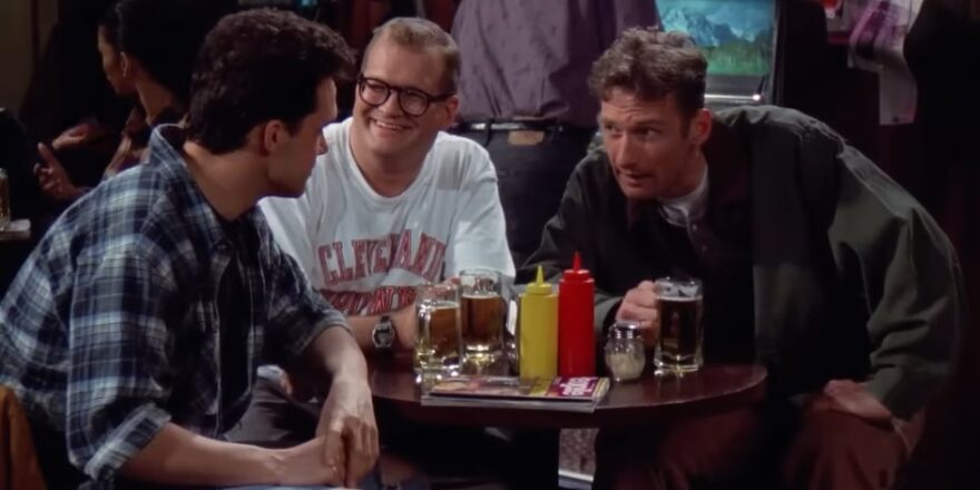 Three men around a table, in a bar.